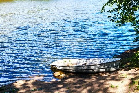 Pleasure boat on the shore of a lake overgrown with trees Stock Photos