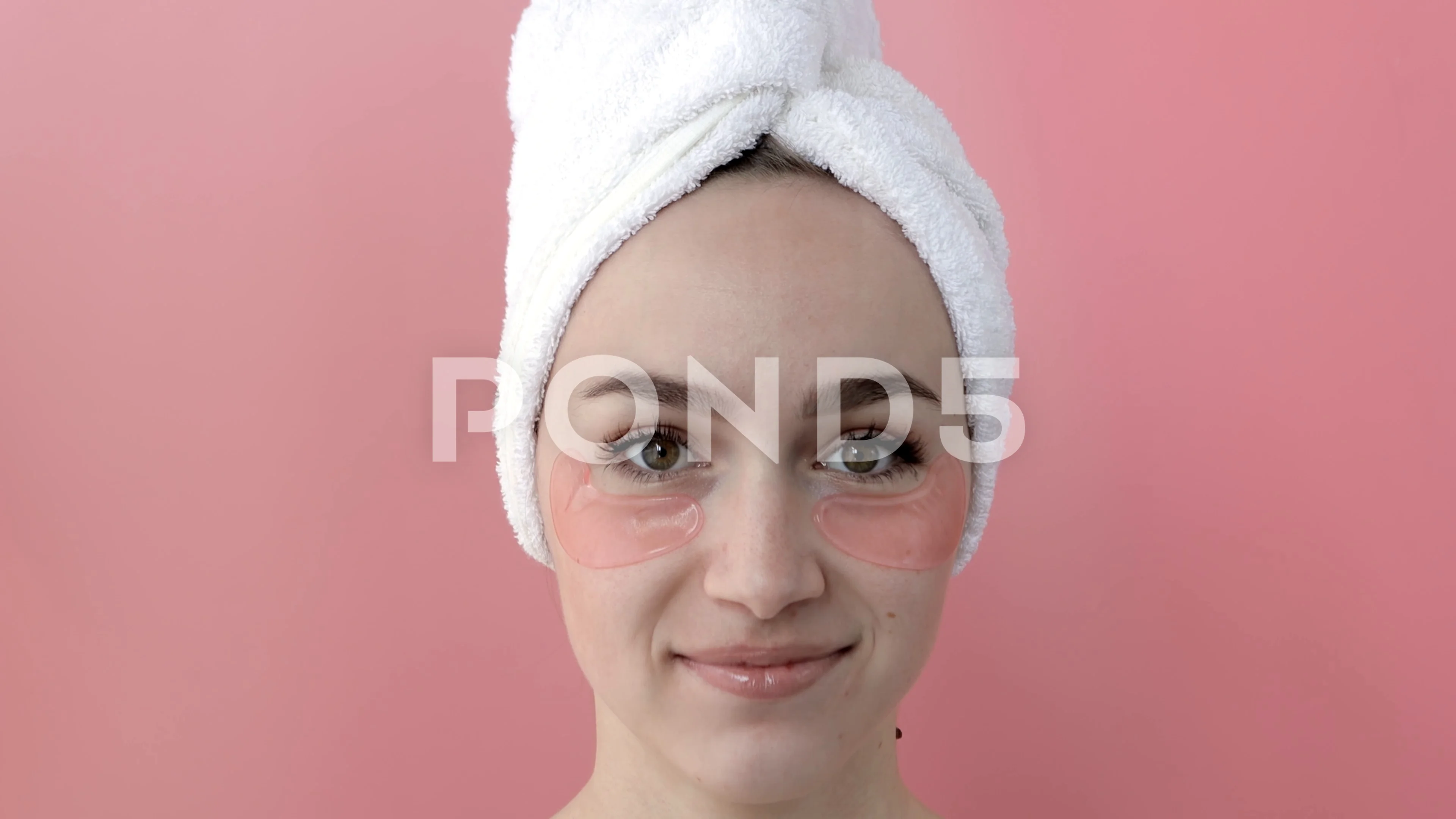 Plesant nude girl applying collagen eye masks on face in front of a mirror.  Port