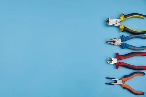 Pliers of different types with a copy space on a blue background. top view Stock Photos