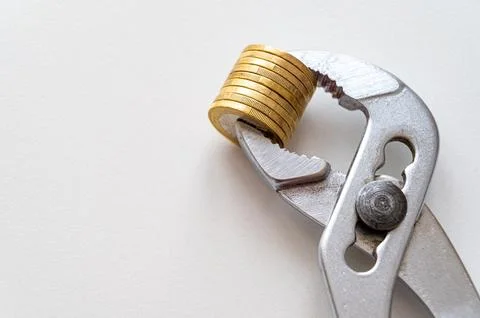 Pliers holding stack of coins. Stock Photos