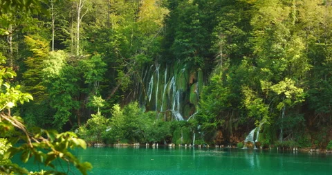 Plitvice waterfall cascades down mossy rocks into blue lake in Croatia during Stock Footage 310238377