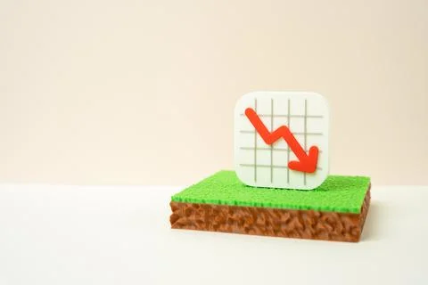 A plot of land and a falling arrow chart. Concept of declining property val.. Stock Photos