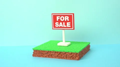 A plot of land is for sale. The plot area has a green lawn and a For Sale sign. Stock Footage 335836948