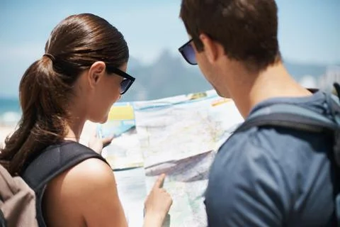 Plotting the best route to the beach. Shot of a young couple looking at a map Fotos de archivo