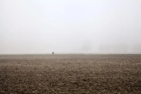 Ploughed field in the fog with a rusty  weir in the distance Stock Photos