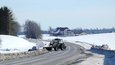 Plow clears snow from road in winter landscape near houses in rural area Stock Footage 330987606
