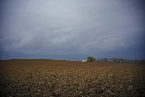 Plowed field landscape under dramatic cloudy sky Stock Photos