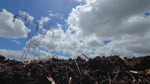 Plowed field texture of dark compost soil below a towering high voltage pylon gr Video stock 343751210