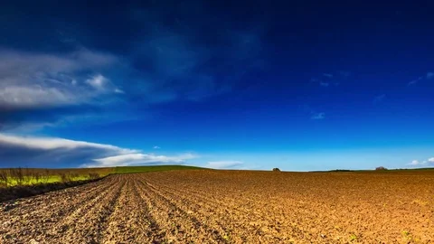 Plowed field under cloudy blue sky Stock Footage 69080844