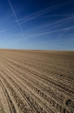 Plowed pattern on the brown field with blue sky Stock Photos