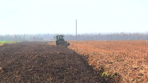 Plowing in the field by a tractor with a trailed unit Stock Footage 145943648