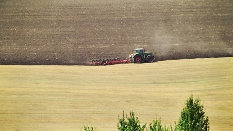 Plowing in the field by a tractor with a trailed unit Stock Footage 145943652