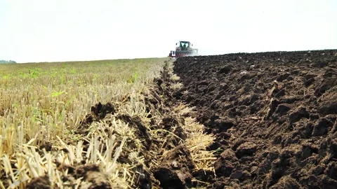 Plowing in the field by a tractor with a trailed unit Stock Footage 145943659