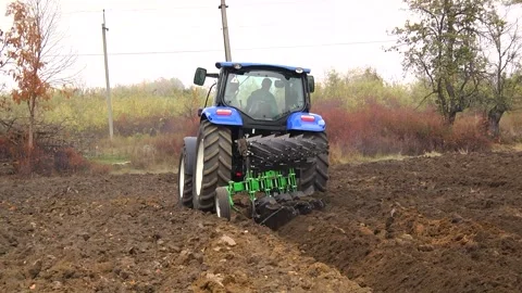 Plowing in the field by a tractor with a trailed unit Stock Footage 145943674