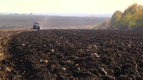 Plowing in the field by a tractor with a trailed unit Stock Footage 145943678