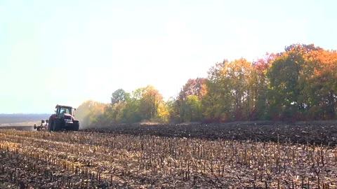Plowing in the field by a tractor with a trailed unit Stock Footage 145943679