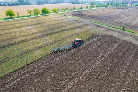 Plowing the ground with a tractor to which a plow is attached, aerial view Stock Photos