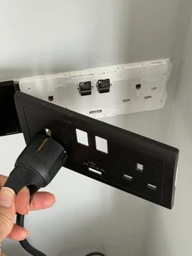 Plug being inserted into loose wall socket with visible wiring, electrical .. Stock Photos