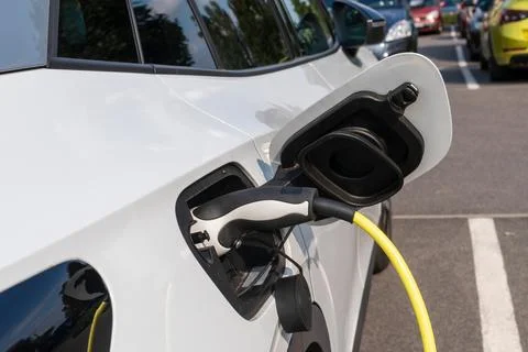 Plug of the charging cable plugged into an electric car Stock Photos