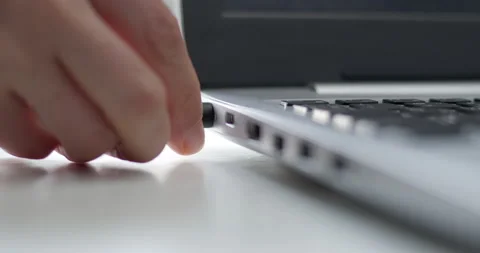 A plug is connected to the laptop to charge the battery. Stock Footage 165920466