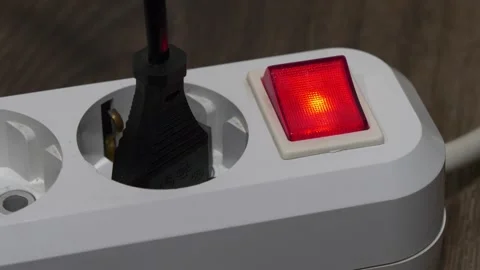 Plug is inserted into the white electric socket with red power indicator Stock Footage 319130463