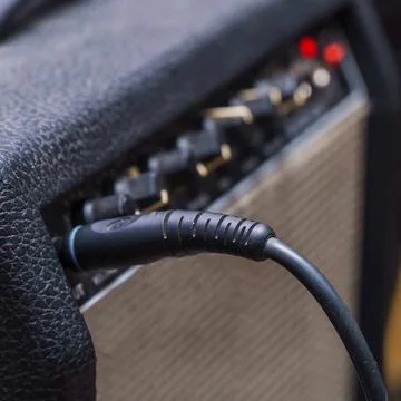 Plug jack with cable plugged into black guitar combo amplifier Stock-Fotos