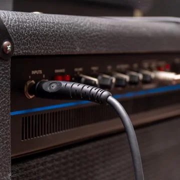 Plug jack with cable plugged into black guitar combo amplifier 스톡 사진