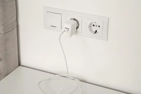 Plug in power socket and light switch on white wall indoors Stock Photos