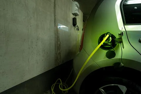 A plugged in electric type 2 wire at the charging socket of an electric car with Stock Photos