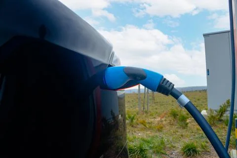 Plugged in Fast EV Charger to the EV car in focus Stock Photos