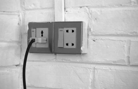 PLUGGED OLD SOCKET ON WHITE BRICK WALL Stock Photos