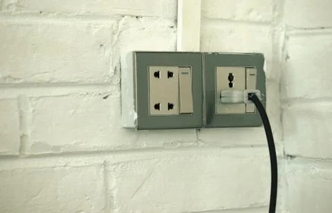 PLUGGED OLD SOCKET ON WHITE BRICK WALL Stock Photos