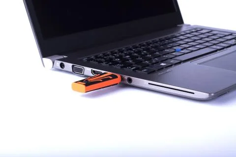 Plugged orange removable flash disk memory into laptop USB slot on white back Stock Photos