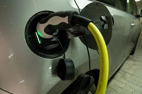 A plugged in type-2 wire charging an electroniv car with ecological produced Stock Photos