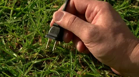 Plugging 110v plug to green grass Stock Footage 20511234