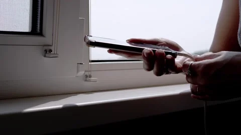 Plugging Charging Cable into Smartphone by Window Stock Footage 317563431