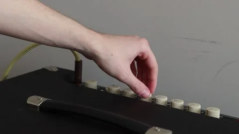 Plugging in a cord into an amplifier and turning knobs Stock Footage 333390501