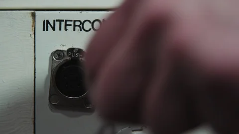Plugging in an intercom headset cable into an audio panel for a studio Stock Footage 89501590