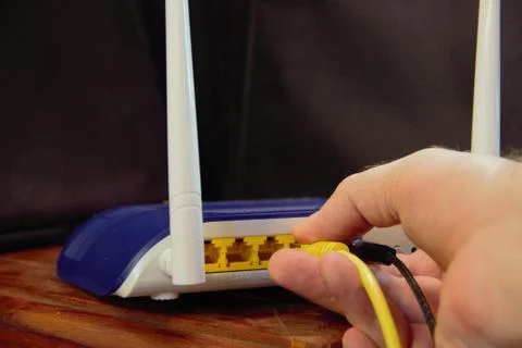 Plugging a network cable into a wifi router 库存照片