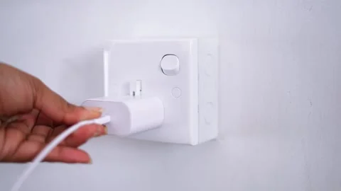 Plugging a phone charger and cable into the electrical outlet on the wall Video stock 297401465