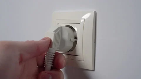 Plugging power electrical plug in electric socket on a white home wall. Conne Stock Footage 169018638