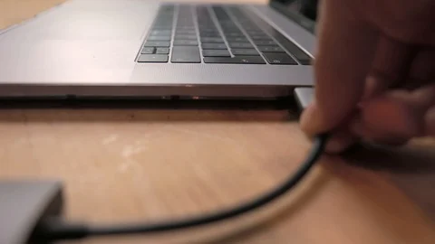 Plugging in usb-c hub into a laptop on wooden desk. Stock Footage 120914569
