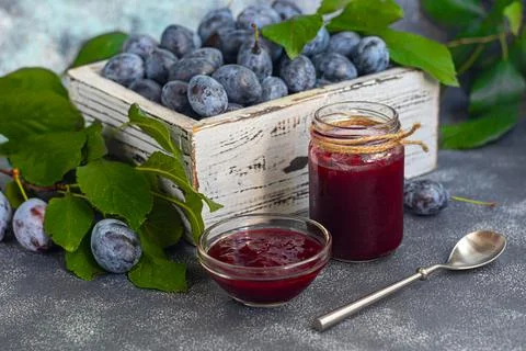 Plum jam in a jar. In the background there are plums. Tkemali sauce. Preparin Stock Photos