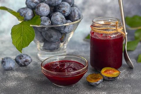 Plum jam in a jar. In the background there are plums. Tkemali sauce. Preparin Fotos de archivo