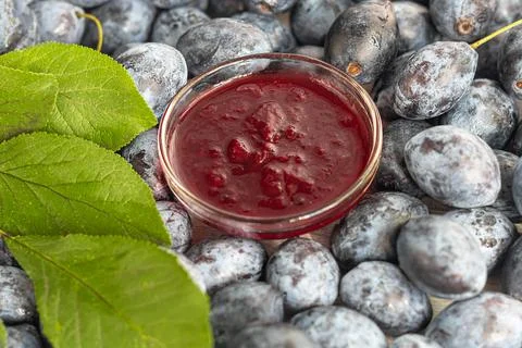 Plum jam in a jar. In the background there are plums. Tkemali sauce. Preparin Fotos de archivo