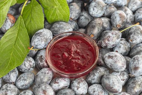 Plum jam in a jar. In the background there are plums. Tkemali sauce. Preparin Fotos de archivo