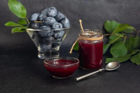 Plum jam in a jar. In the background there are plums. Tkemali sauce. Getting  Fotos de archivo
