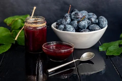 Plum jam in a jar. In the background there are plums. Tkemali sauce. Getting  Fotos de archivo