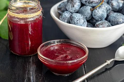 Plum jam in a jar. In the background there are plums. Tkemali sauce. Getting  Stock Photos