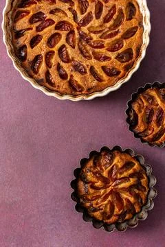 A plum pie is placed on a table with thinly sliced plums visible on top. Bowl Stockfoto's